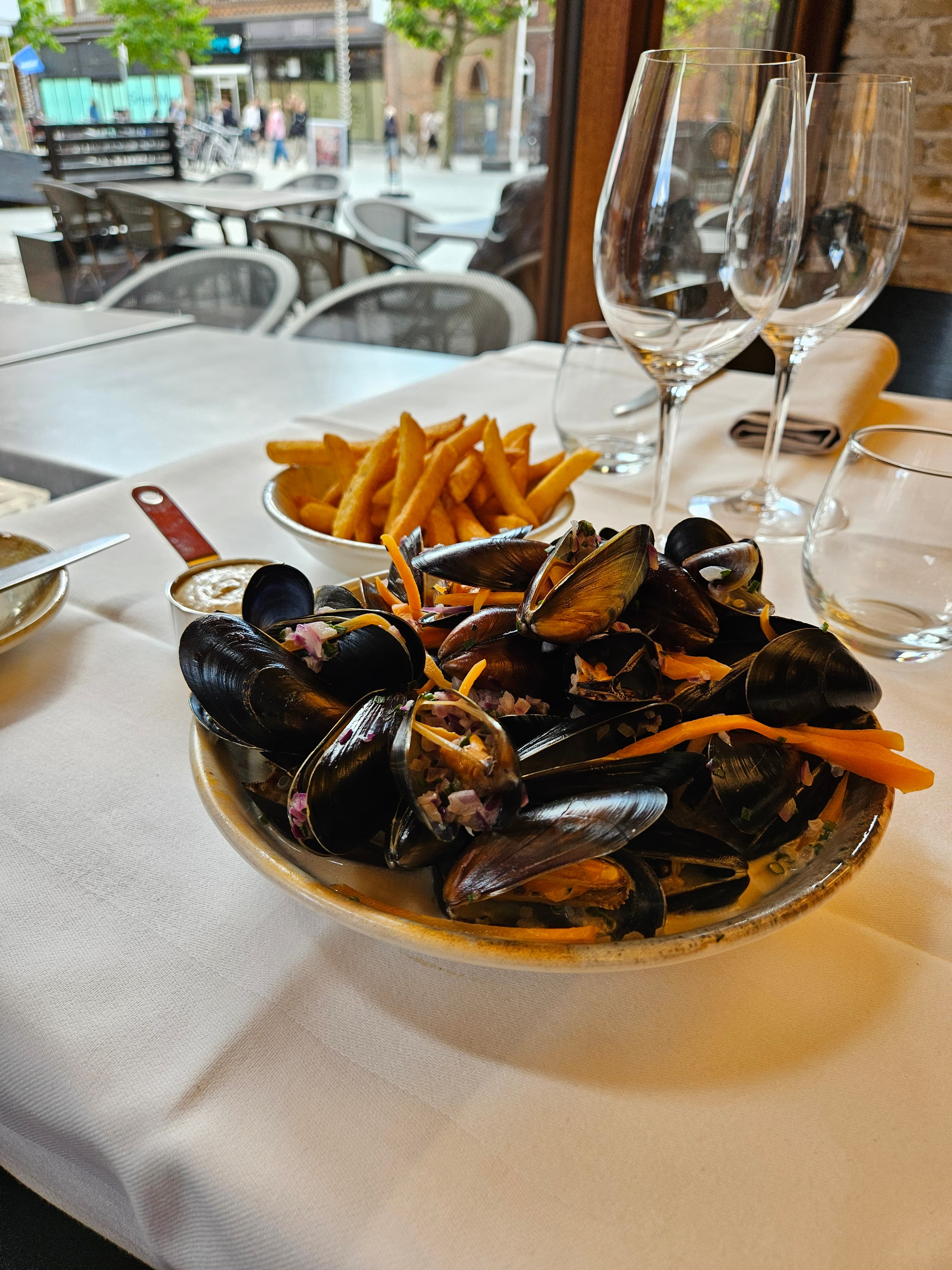 En skål dampede blåmuslinger med pommes frites ved vinduesbordet