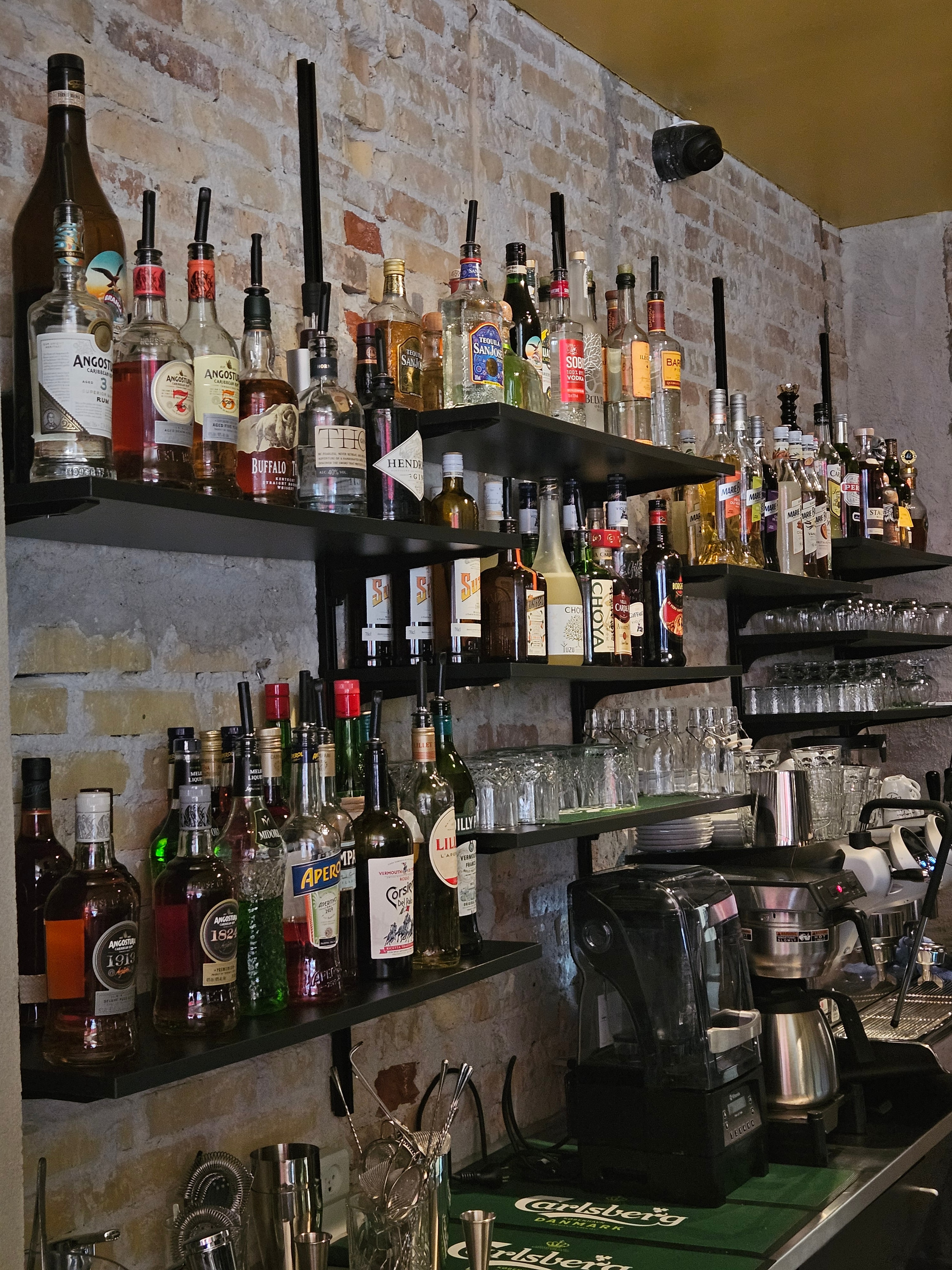 Spiritusflasker og cocktailværktøj opstillet bag baren